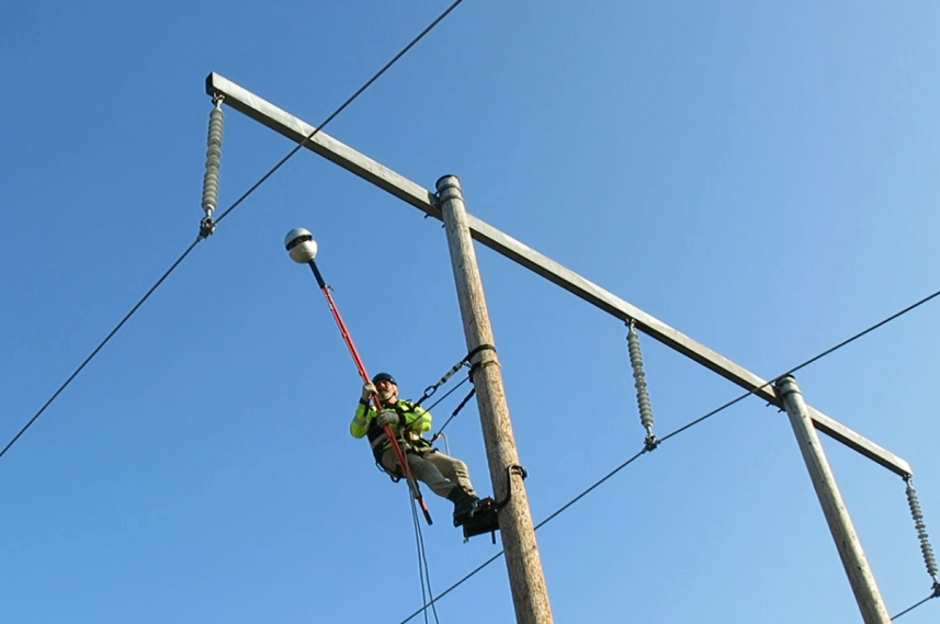 Photo of a man during the installation of the energy self-sufficient sensor under high voltage
