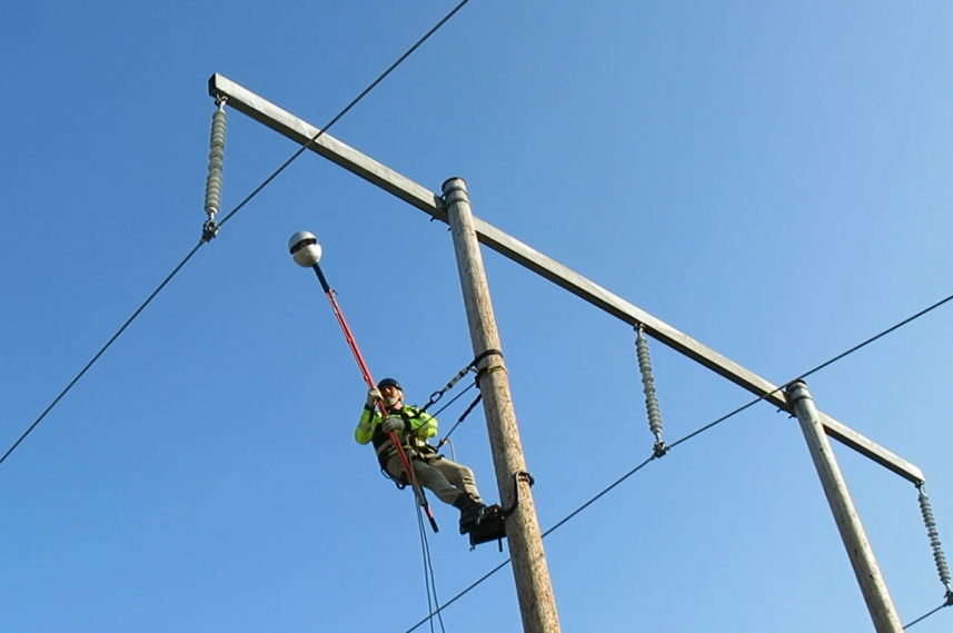 Foto eines Mannes bei der Montage des energieautaken Sensors unter Hochspannung