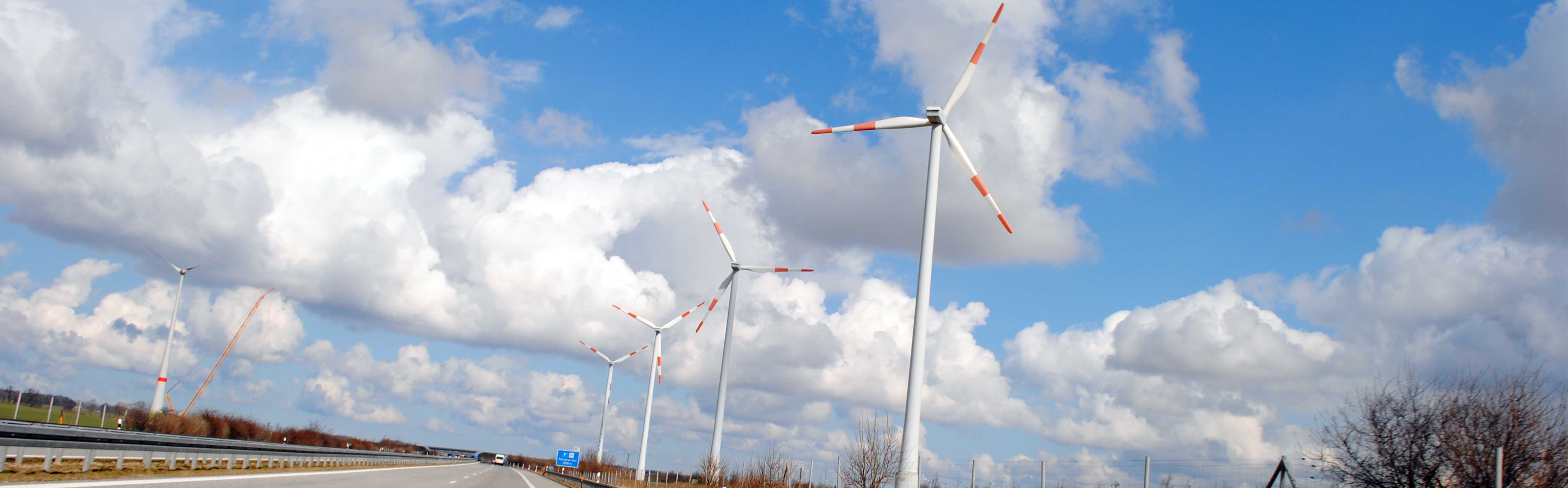 Photography of a highway with wind turbines on the edge with blue sky 